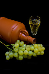 Crystal glass with white wine, bottle and bunch of white grapes