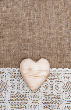 Burlap background with lacy cloth and wooden heart