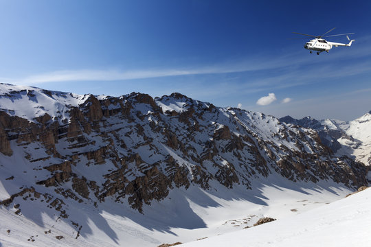 Helicopter in snowy sunny mountains