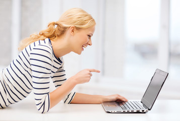 smiling student girl pointing her finger at laptop
