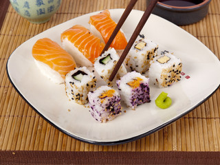 Fresh sushi and sashimi on a plate with chopsticks and soy sauce