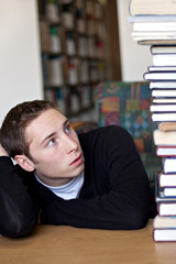 Student Looking Up At Pile of Books