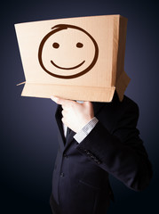 Businessman gesturing with a cardboard box on his head with smil