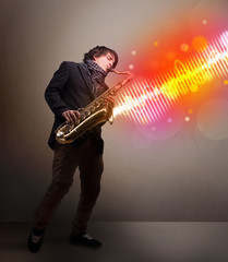Young man playing on saxophone with colorful sound waves
