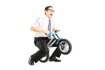 Fototapeta na wymiar Excited young businessman riding a small bicycle