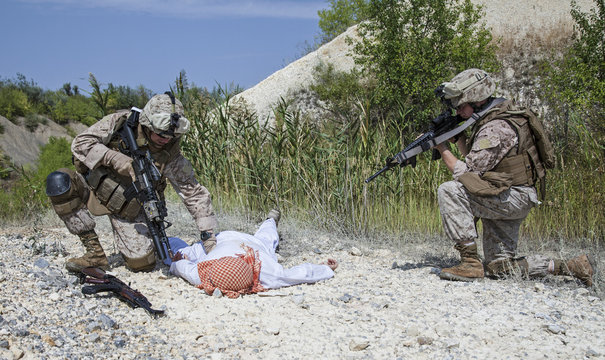 Soldiers examining dead terrorist lying on ground