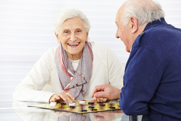 Happy senior couple playing checkers