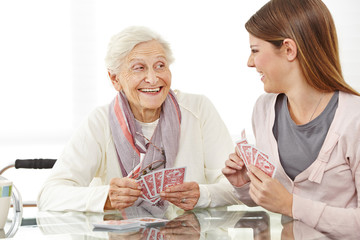Senior woman playing cards with caregiver