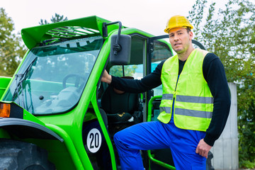 Builder on site in front of  construction machinery