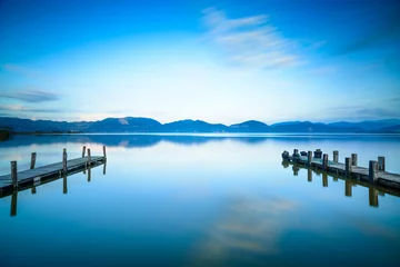 Foto op Plexiglas Twee houten pier of steiger en op een blauwe meerzonsondergang en luchtrefle © stevanzz