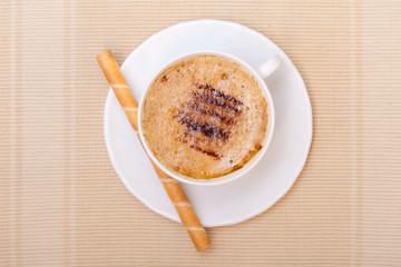 White cup coffe and waffle roll with cream on brown background