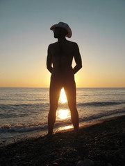 Naked man on the seashore take a sunshine bath