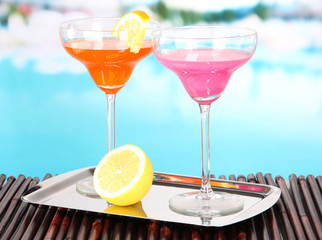 Glasses of cocktails on table near pool