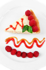 Slice of cheesecake with raspberry on plate, isolated on white