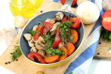Sliced fresh vegetables in pan on wooden board isolated on