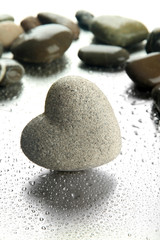 Fototapeta na wymiar Szary kamień w kształcie serca, na tle światła