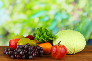 Different fruits and vegetables on table on wooden background