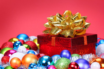 Christmas Gift with Gold Bow and Colorful Balls over red