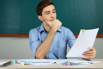 Young teacher review tests in school classroom