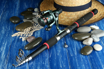 Fishing rod, gumboots and hat on wooden table close-up