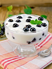 Yogurt is thick with black currants and spoon on the board