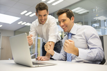 Two Successful business man with arms up, in the office