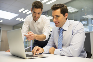 Two coworkers businessmen working together on laptop ,office