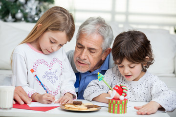 Grandfather Assisting Children In Writing Letters To Santa Claus