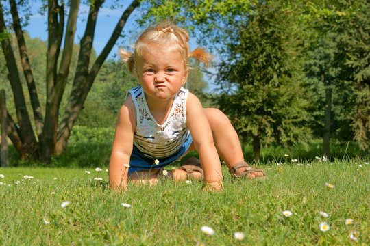 Child, girl having fun on the meadow, with a grimace on his face