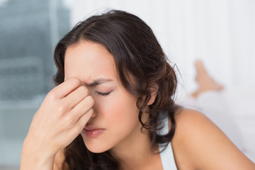 Fototapeta premium Woman suffering from headache with eyes closed at home