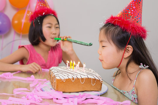 Girls Blowing Noisemaker And Birthday Candles