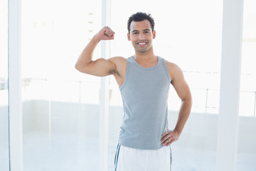 Fototapeta na wymiar Fit young man flexing muscles in fitness studio