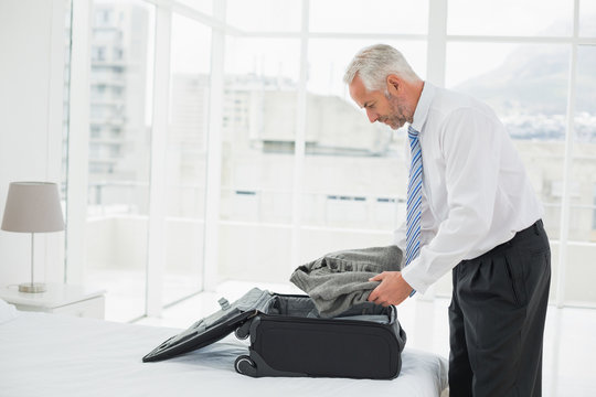 Musinessman Unpacking Luggage At A Hotel Bedroom