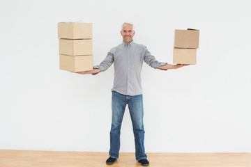 Smiling mature man carrying boxes in a new house