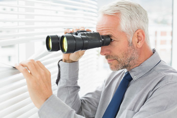 Fototapeta na wymiar Businessman peeking with binoculars through blinds