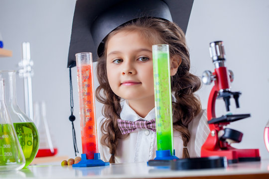 Curious little girl posing with microscope in lab