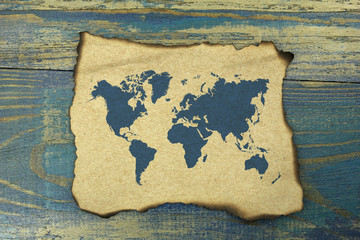 world map on burnt paper on blue old wood background
