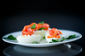 boiled egg with salty salmon on black background