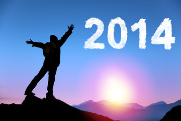 happy new year 2014.happy young man standing on the top of mount