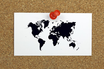 push pin holding a card with world map on a cork board