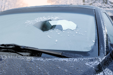 winter driving - scraping ice from a windshield