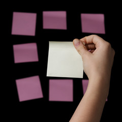 Obraz premium female teen hand holding yellow sticky note agains pinks