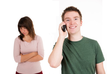 Mann mit Handy, enttäuschte Freundin im Hintergrund