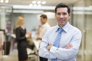 Businessman posing while colleagues talking in background