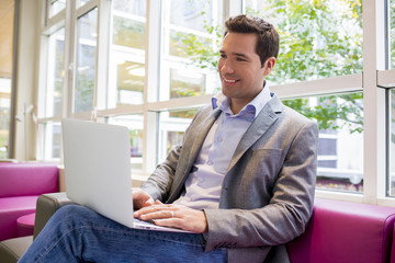 Happy smiling young Businessman  working with Laptop on sofa