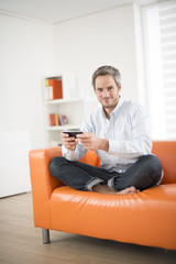 attractive man smiling and phone  on a couch