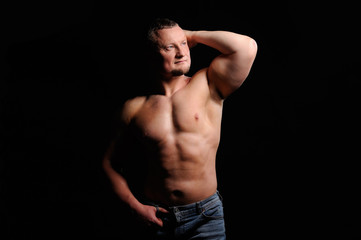 Naklejka na ściany i meble Muscular male posing on black background