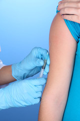 doctor holding syringe with vaccine into patient's shoulder