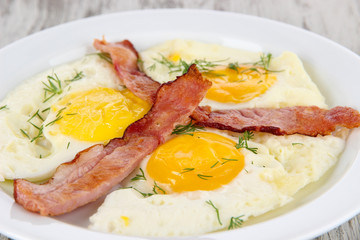 Scrambled eggs and bacon on plate on wooden table