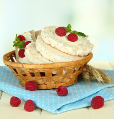 Tasty crispbread with berries in wicker basket, on white table